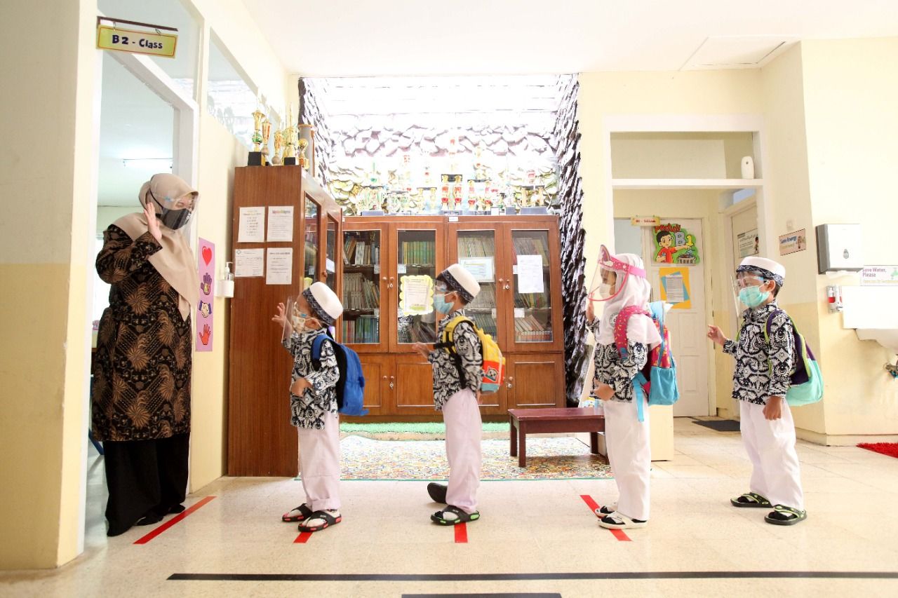 SISWA Darul Hikam Kindergarten and Pre-K menjaga jarak saat masuk kelas.