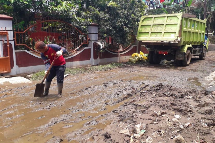 Petugas Dinas Pekerjaan Umum membersihkan tanah lumpur sisa luapan sungai Ciwarga di Perumahan Griya Indah Sukaraja Kecamatan Cicendo Kota Bandung.