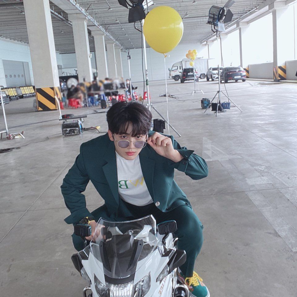 Potret Kim Yo-han sedang mengendarai motor sambil memegang balon kuning