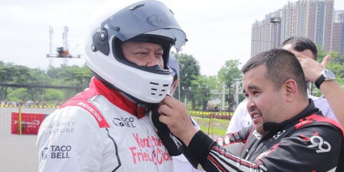 Akbar Rais memasangkan helm kepada Bambang Soesatyo sebelum mengikuti kejurnas drifting di Kawasan Meikarta, Kabupaten Bekasi, Sabtu 28 November 2021.*