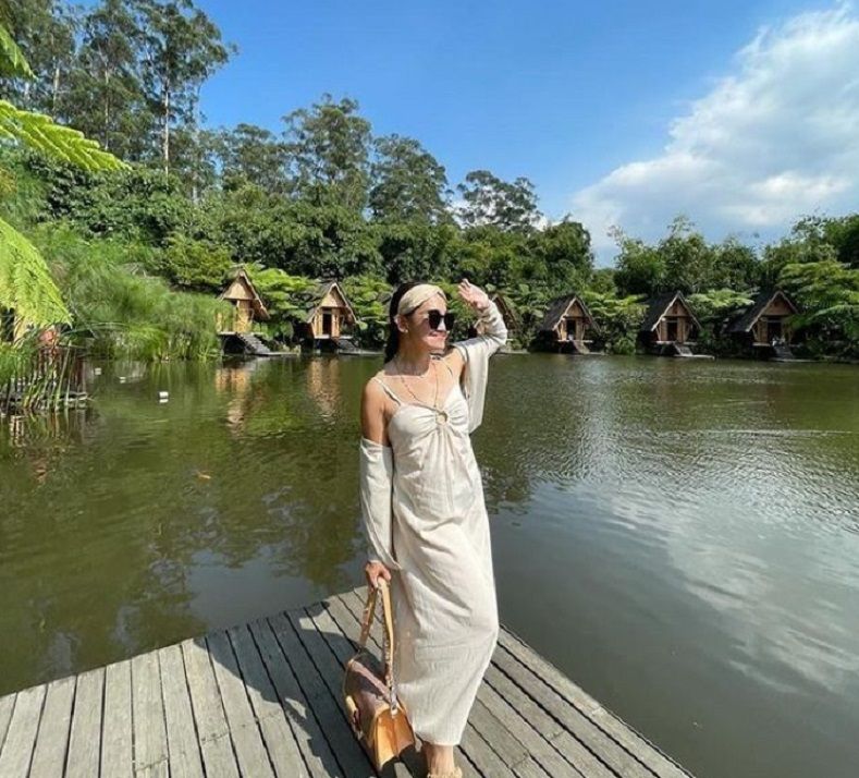 Ilustrasi: Perempuan tengah berswafoto di pinggir danau yang berada di tempat wisata Dusun Bambu, Bandung.