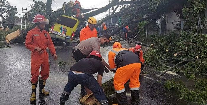Anggota BPBD Kota Tasikmalaya dibantu TNI dan Polri mengevakuasi pohon tumbang yang menimpa mobil di Jalan Ibrahim Aji, Kampung Ciropoh, Kelurahan Sukamaju Kidul, Kecamatan Indihiang, Kota Tasikmalaya, Minggu 9 Januari 2021.*