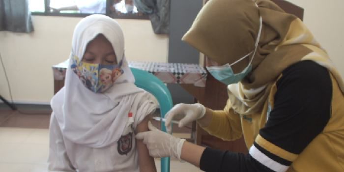 Anak perempuan yang disuntik vaksin oleh seorang nakes di Banyumas nampak tenang.