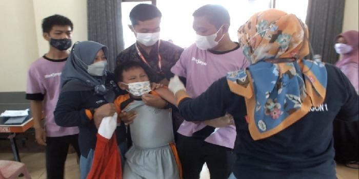 Seorang anak usia 6-11 tahun yang disuntik vaksin Sinovac di Gedung UPK Wangon nampak meronta karena takut jarum suntik, namun usai disuntik anak tersebut senyum seperti sediakala.