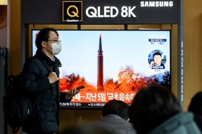 Seorang pria berjalan melewati siaran berita yang menunjukkan cuplikan uji coba rudal Korea Utara, di stasiun kereta api di Seoul pada 11 Januari 2022.