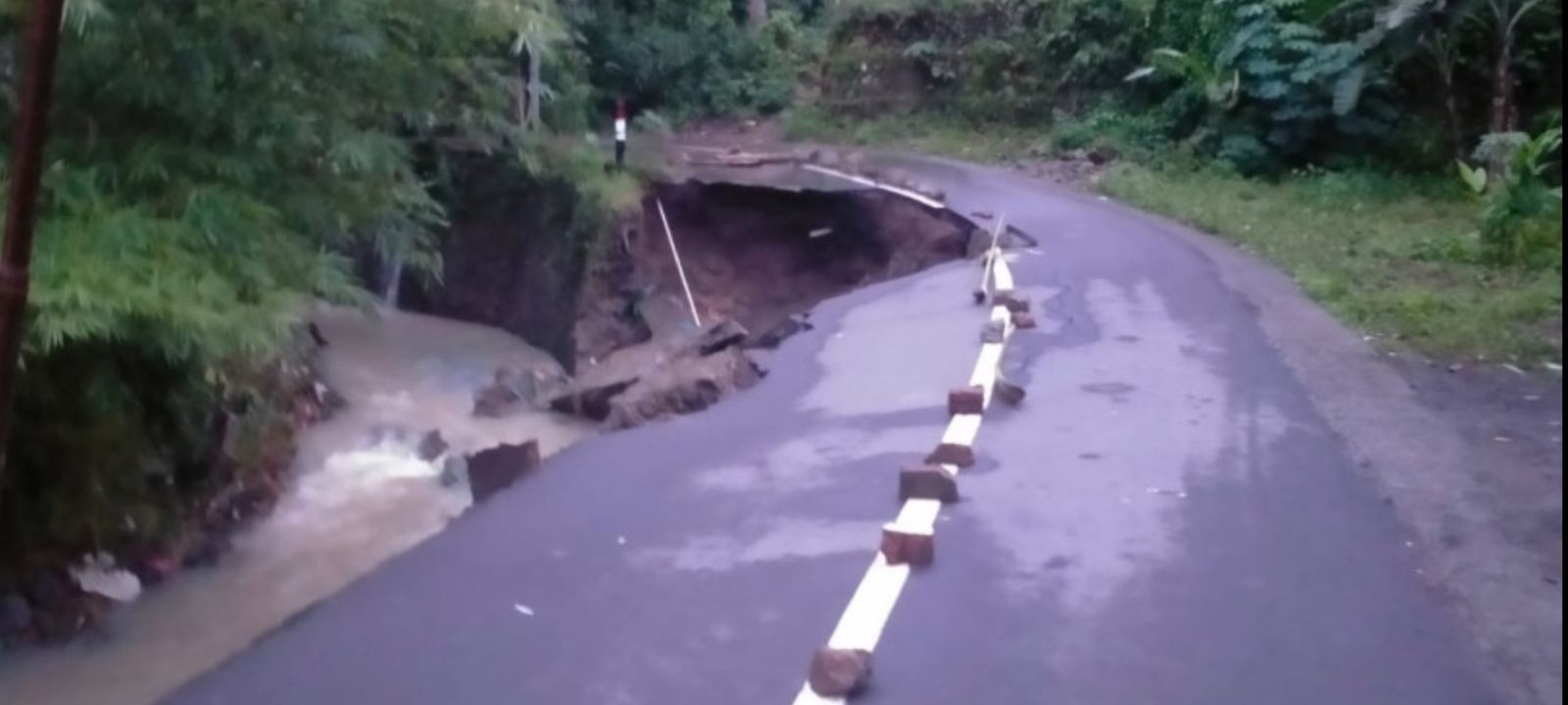 Kondisi jalan yang amblas akibat lapisan tanah tergerus arus banjir di Kecamatan Batu Layar, Kabupaten Lombok Barat, Provinsi Nusa Tenggara Barat.