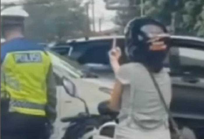 Seorang wanita pengendara motor mengacungkan jari tengahnya saat ditegur anggota polisi