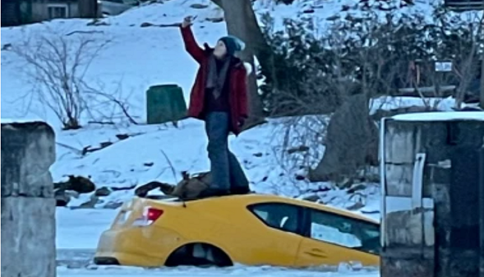 Seorang wanita di Kanada malah asyik selfie dengan berdiri di atas mobil yang tenggelam di es.