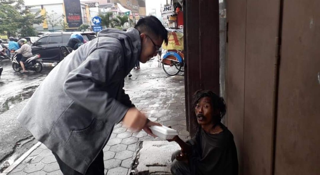 Seorang anak muda sedang menunjukkan kepeduliannya dengan berbagi makanan dengan seorang pria gelandangan/facebook/ Rexi Andalangi Maatuil