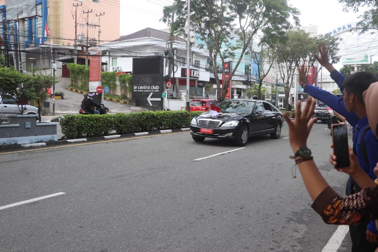 Warga Kota Balikpapan di kawasan Jenderal Sudirman melambaikan tangan ketika melintas mobil Kepresidenan, Minggu 13 Maret 2022 sore. 