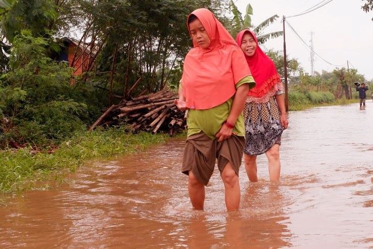 Dua orang ibu menerobos genangan air  sisa banjir luapan sungai Cikeruh yang mulai surut Selasa 15 Maret 2022 di Kampung Sapan Desa Tegalluar Kecamatan Bojogsoang Kabupaten Bandung yang tergenang sejak Minggu 13 Maret 2022.