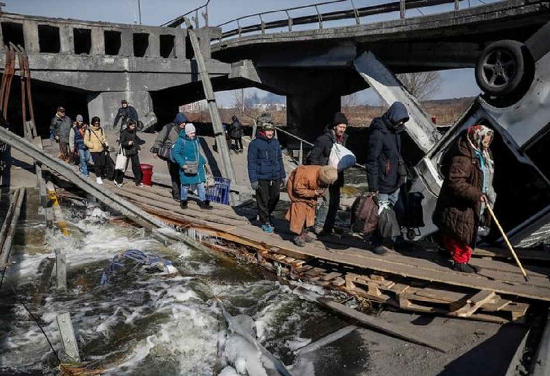 Warga menyeberangi sungai Irpin di dekat jembatan yang hancur pekan lalu saat mereka melarikan diri dari Ukraina./