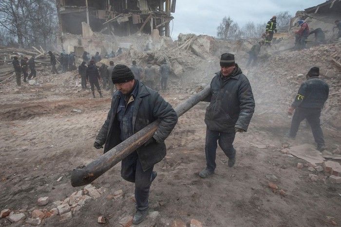 Orang-orang membersihkan puing-puing dari pangkalan militer yang rusak di Okhtyrka di wilayah Sumy, Ukraina. 