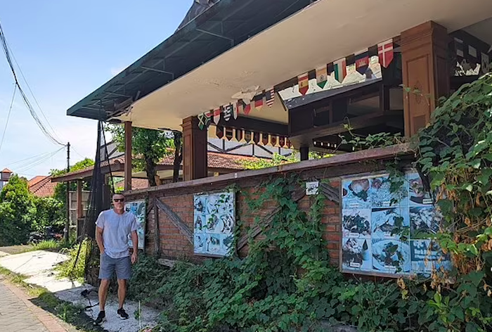 Seorang wisatawan Australia berpose di depan hotel yang ditumbuhi rerumputan dan ilalang di Bali.