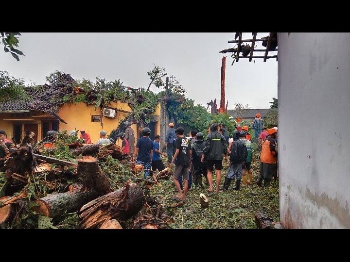 Warga sekitar membantu angkat batang pohon yang tumbang akibat hujan deras dan angin kencang  yang menimpa rumah di Sleman/ Foto: Desi Dwiarti/ SeputarTangsel