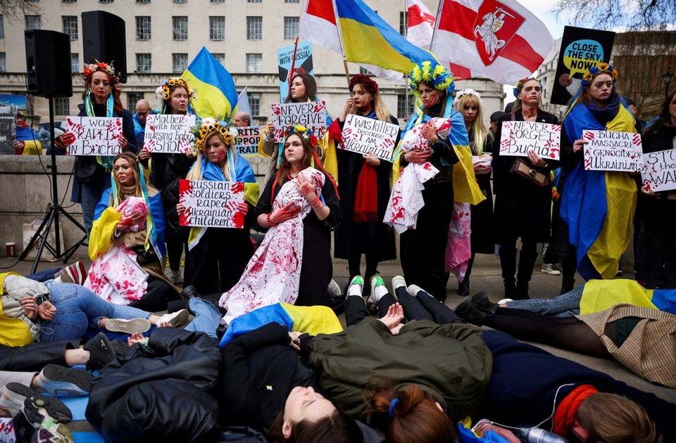 Warga berunjuk rasa memegang plakat dengan slogan menentang pembantaian di Bucha selama berlangsungnya demonstrasi pro-Ukraina, di tengah invasi Rusia ke Ukraina, di luar Downing Street, di London, Inggris, 9 April 2022.  