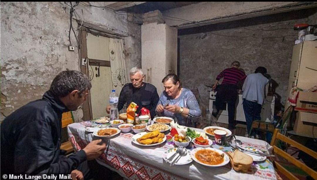 Svetlana (tengah), bersantap di meja bersama teman-teman dari desa di bunker bawah tanah. (Kiri-Kanan) - Ashot Mktrychan,42, Valery Slesarevsky,58, Svetlana Ginzhul,54, (latar belakang) Alla Mktrychan dan Larisa Slesaresvska, 56./   
