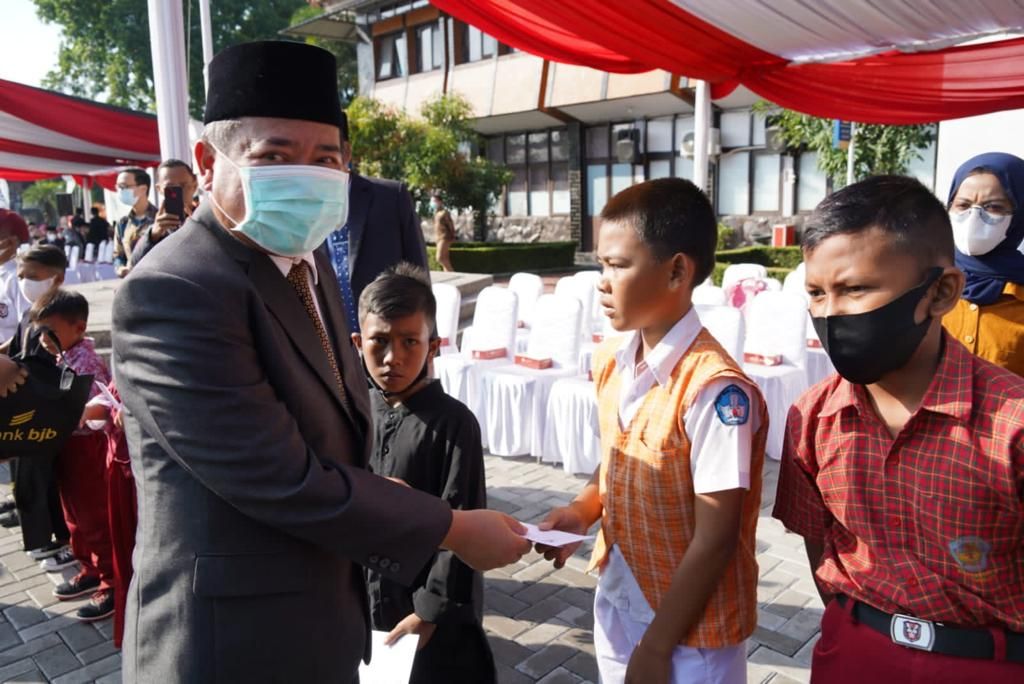 Bupati Garut, Rudy Gunawan memberikan santunan kepada salah seorang siswa saat upacara Hardiknas, Jumat 13 Mei 2022. Bupati menegaskan bahwa hepatitis bukan penyakit yang membahakan sehingga PTM 100 Persen tetap dilaksanakan.*