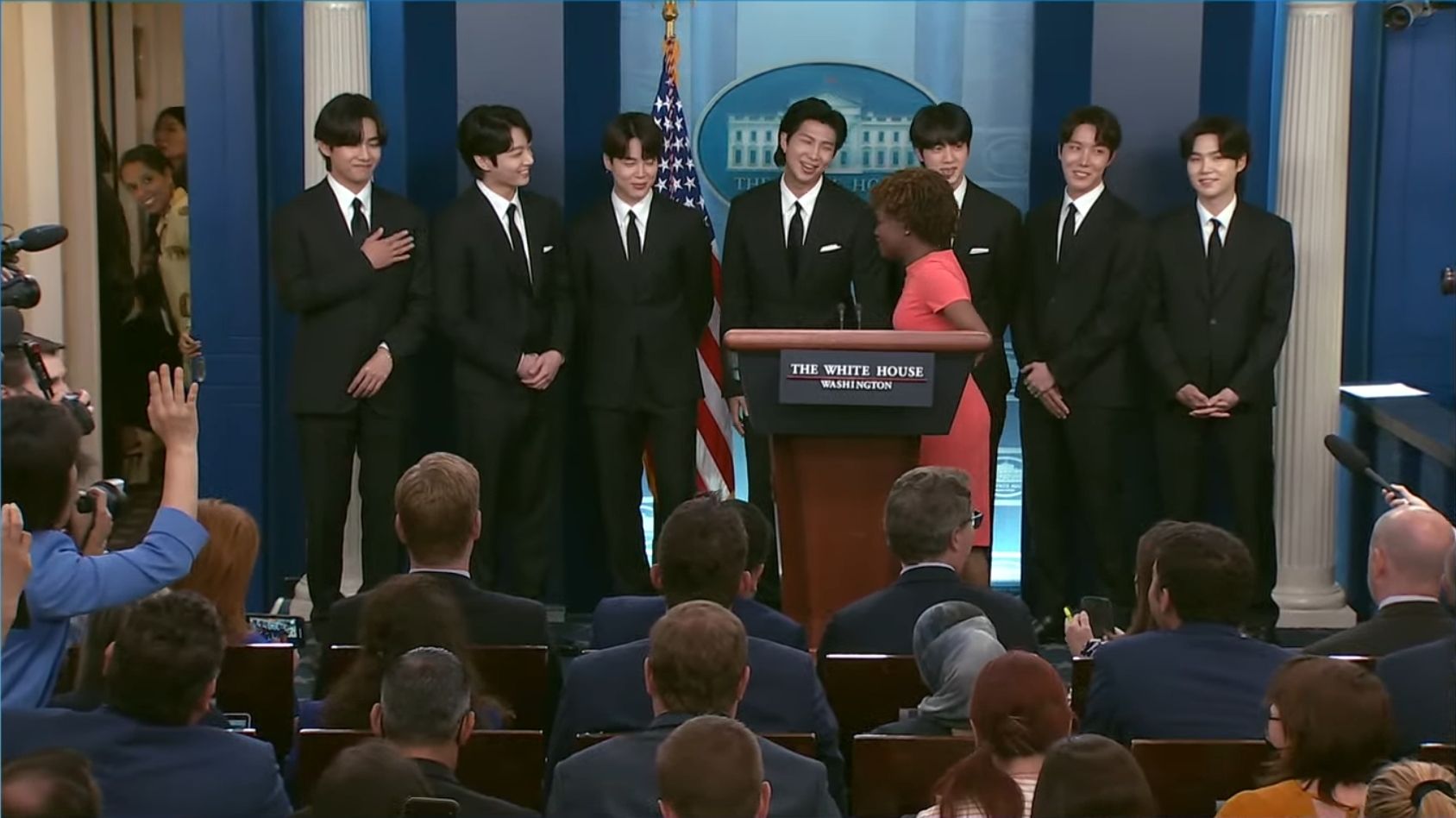 Dari kiri ke kanan: V BTS, Jungkook, Jimin, RM, Jin, J-Hope, dan Suga dengan Sekretaris Pers Karine Jean-Pierre (tengah).  |  Gedung Putih/YouTube