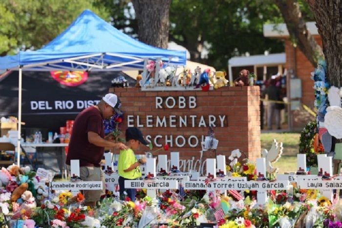 Seorang pria dan seorang anak memberikan penghormatan kepada para korban penembakan massal di Sekolah Dasar Robb pada 28 Mei 2022 di Uvalde, Texas. 