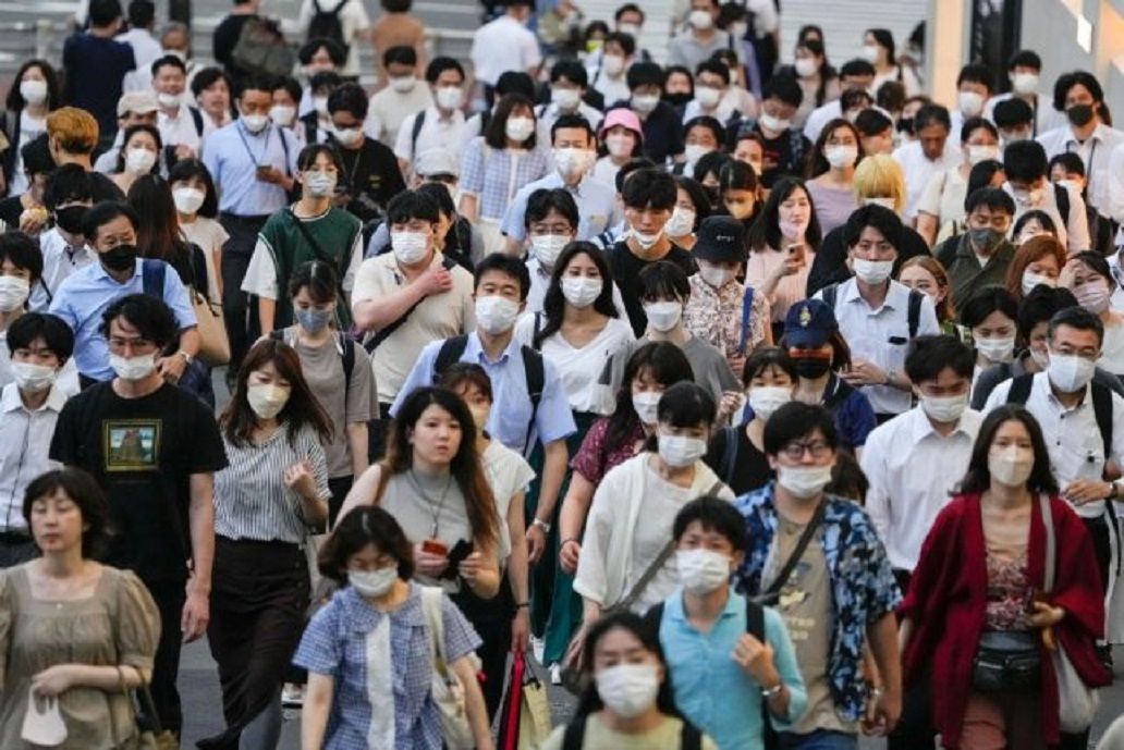Warga mengenakan masker pelindung berjalan menuju stasiun kereta api Shinjuku setelah bekerja di Tokyo, Jepang pada hari Kamis. Tokyo mencatat rekor 40.406 kasus baru hari itu dan angka nasional 233.100.  
