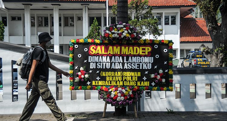 Warga berjalan di samping karangan bunga untuk terdakwa kasus penipuan investasi opsi biner Quotex Doni M. Taufik alias Doni Salmanan yang tengah menjalani sidang dakwaan di Pengadilan Negeri Bale Bandung, Baleendah pada Kamis, 4 Agustus 2022.