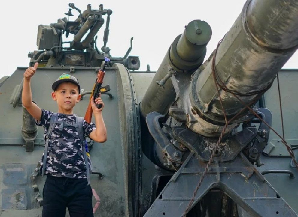 Seorang anak sekolah, Lev Morilyi menggenggam erat mainannya AK-47 pada tank Rusia yang hancur kemarin saat dia menyatakan: 'Kami akan mengalahkan Putin'./  