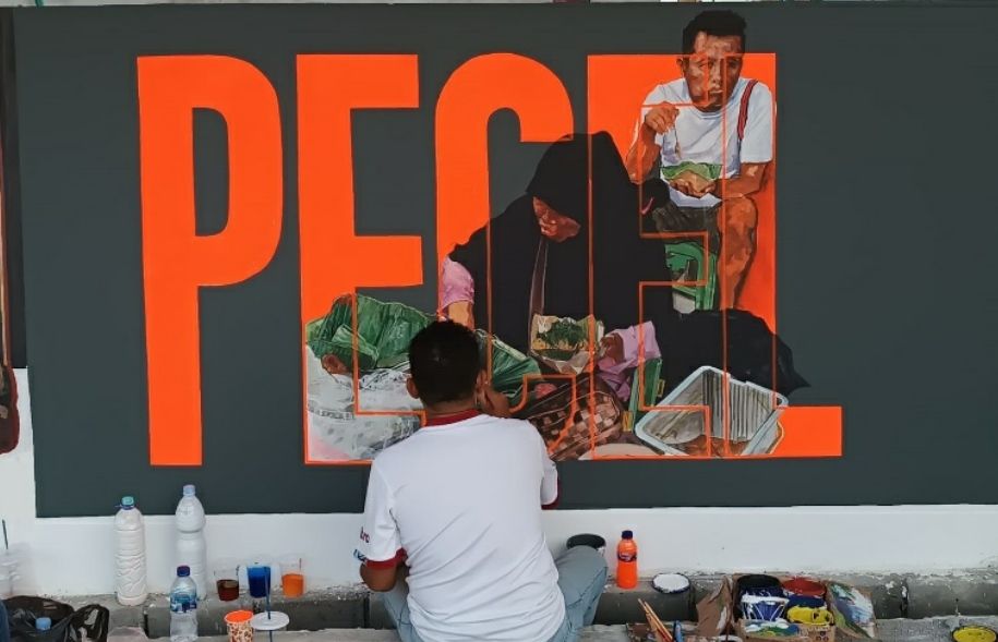 Sutarno sedang menyelesaikan lukisan mural berjudul Pecel