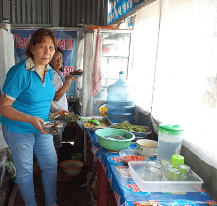 Pemilik Warung Makan Pojok sedang melayani pembeli yang selalu ramai dikunjungi setiap hari. 