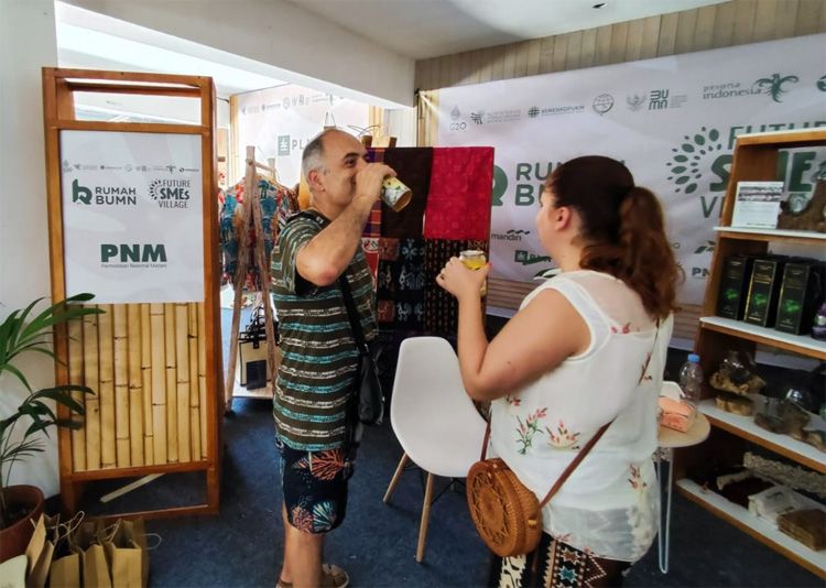 Wisatawan asing mencicipi produk UMKM binaan PT Permodalan Nasional Madai yang mengikuti pameran di arena KTT G20, Nusa Dua, Bali.