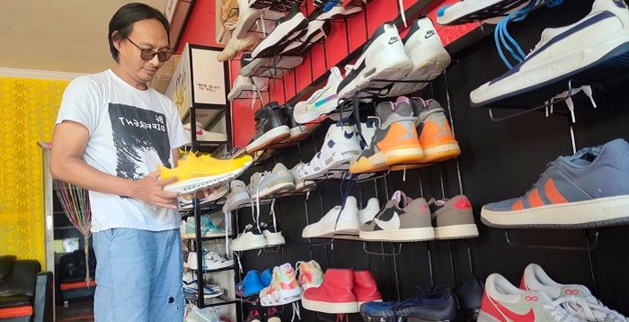 Seorang pedagang thrifting produk sepatu, Irvan Nurdin (43), menata barang jualannya di kiosnya, Kampung Ciroyom, Kelurahan Parakanyasag, Kecamatan Indihiang, Kota Tasikmalaya, Senin 22 November 2022.*