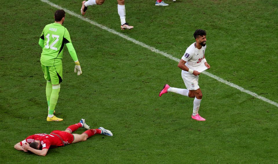 Ramin Rezaeian dari Iran merayakan gol kedua mereka saat Ben Davies dan Danny Ward dari Wales terlihat sedih.*  