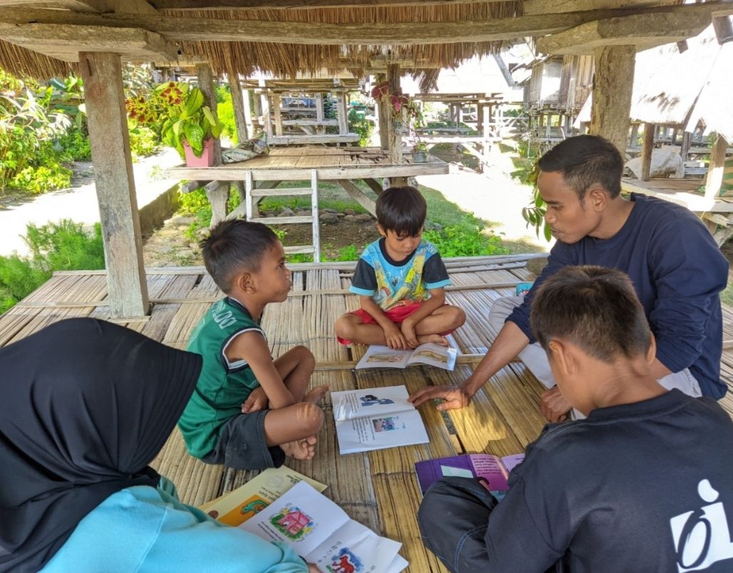 Ahmad, pegiat pendidikan di Kecamatan Wawo, Kab. Bima, Nusa Tenggara Barat, mengajak anak-anak membaca buku di Uma Lengge Mengajar