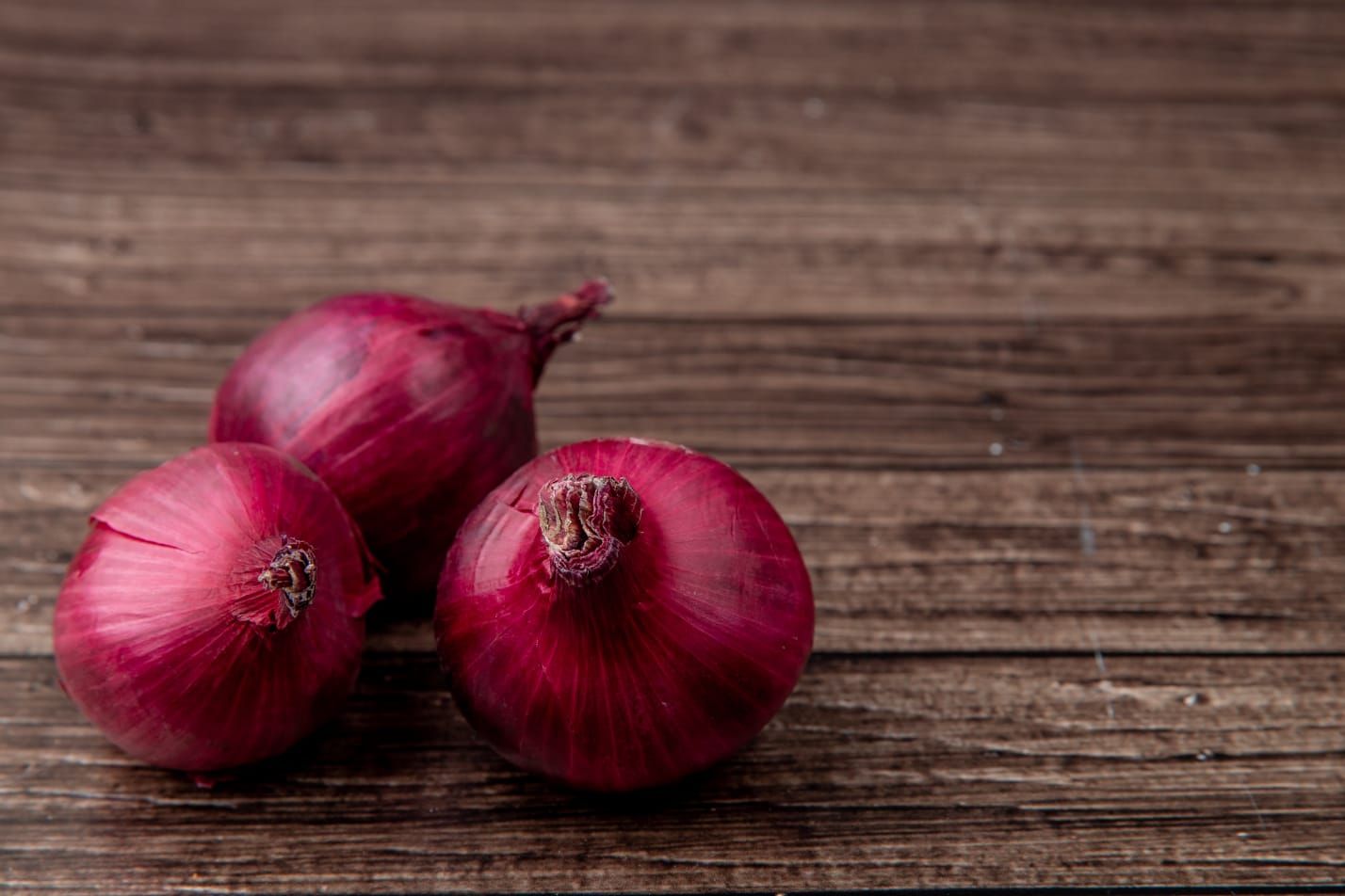 Tampilan samping bawang merah di sisi kiri dan latar belakang kayu. / freepak@stockking