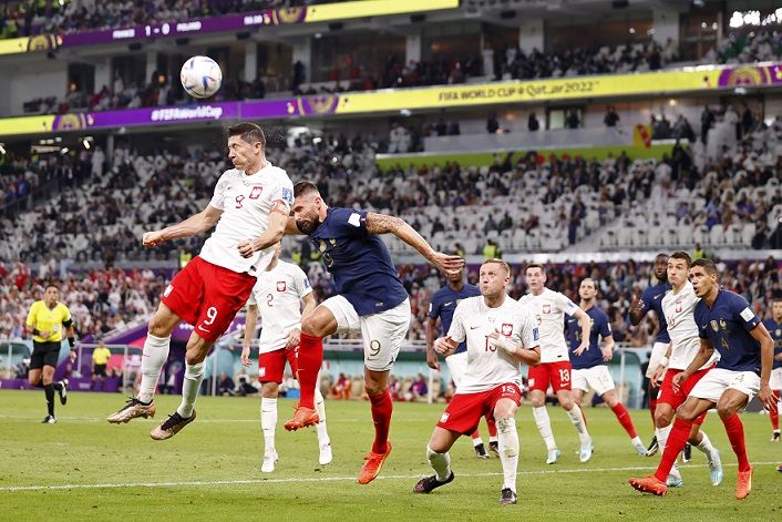Penyerang Polandia Robert Lewandowski (9) menyundul bola melawan penyerang Prancis Olivier Giroud (9) pada paruh kedua babak enam belas pertandingan Piala Dunia FIFA 2022 di Stadion Al Thumama, pada Minggu 4 Desember 2022; di Doha, Qatar.