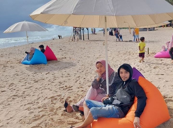 Pasangan muda-mudi menikmati keindahan Pantai Kelapa Warna