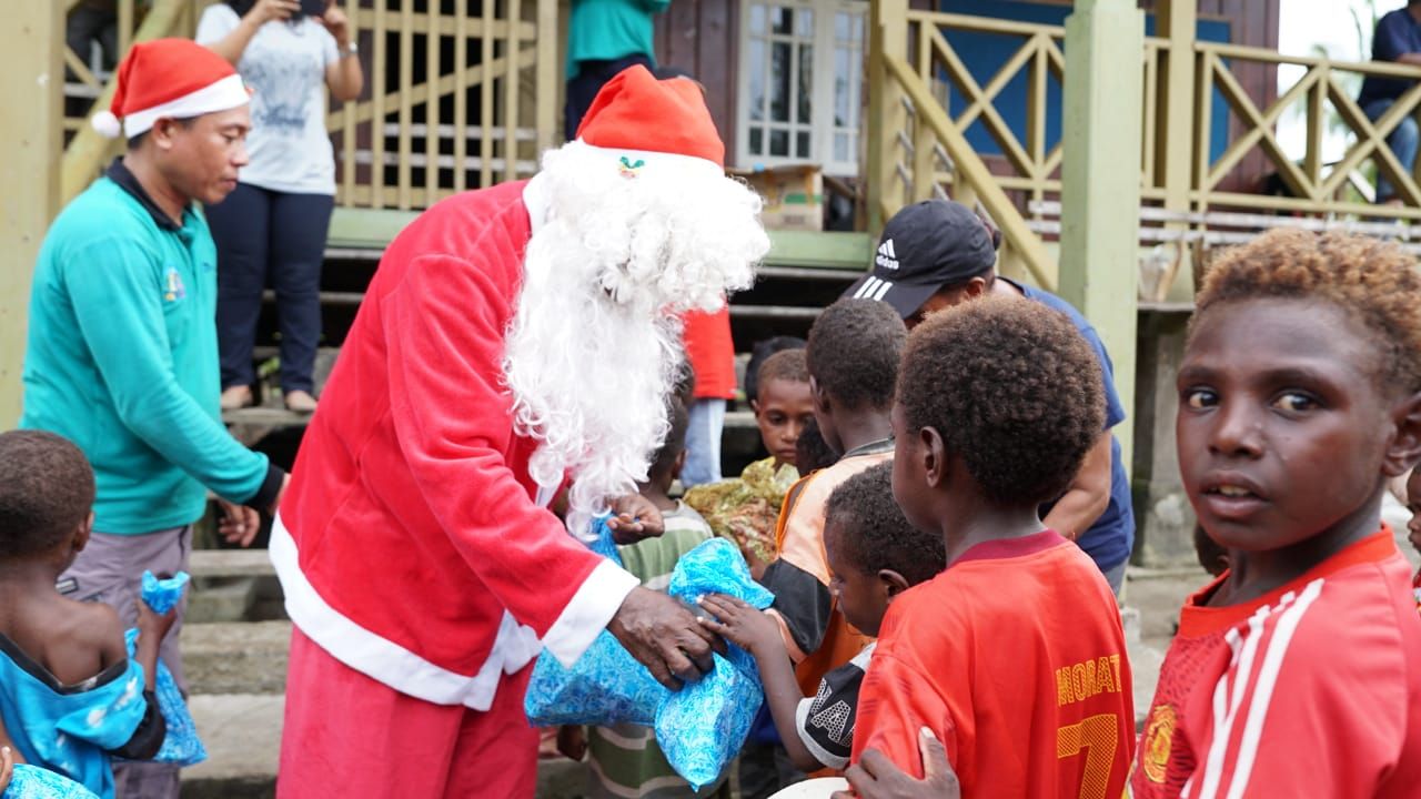 Suasana saat Kepala Distrik Mimika Timur Jauh (MTJ) Julius Katagame, S.Sos sebagai Santa Claus untuk berbagi bingkisan Natal kepada anak-anak pesisir di Kabupaten Mimika.
