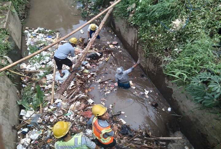 Petugas yang disiagakan Astra Tol Tangerang Merak saat membersihkan tumpukan sampah di drainase di sekitar jalan tol. 