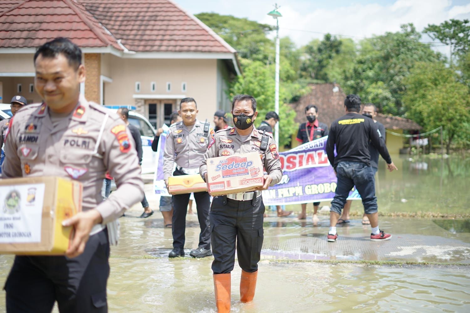 Aparat Satlantas Polres Grobogan saat mendistribusikan bantuan sembako kepada korban terdampak banjir di Mlakas, Lemahputih, Brati.