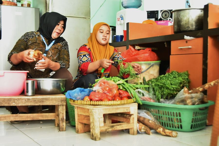 Zulfa (kanan) saat bekerja di dapur permakanan Dinsos Surabaya.
