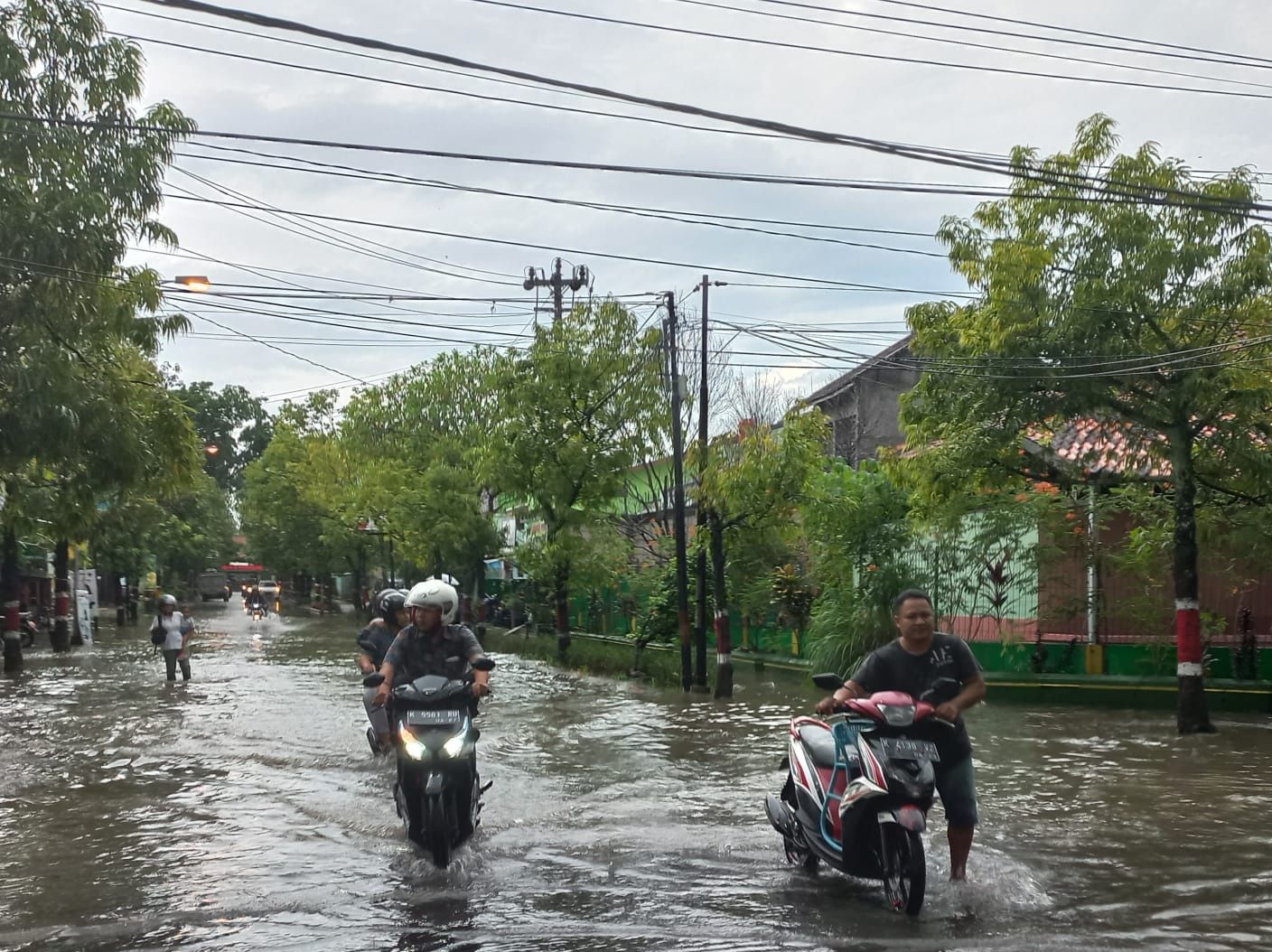 Seorang pengendara mendorong motornya yang mogok setelah menerjang banjir di Jl Kartini Purwodadi