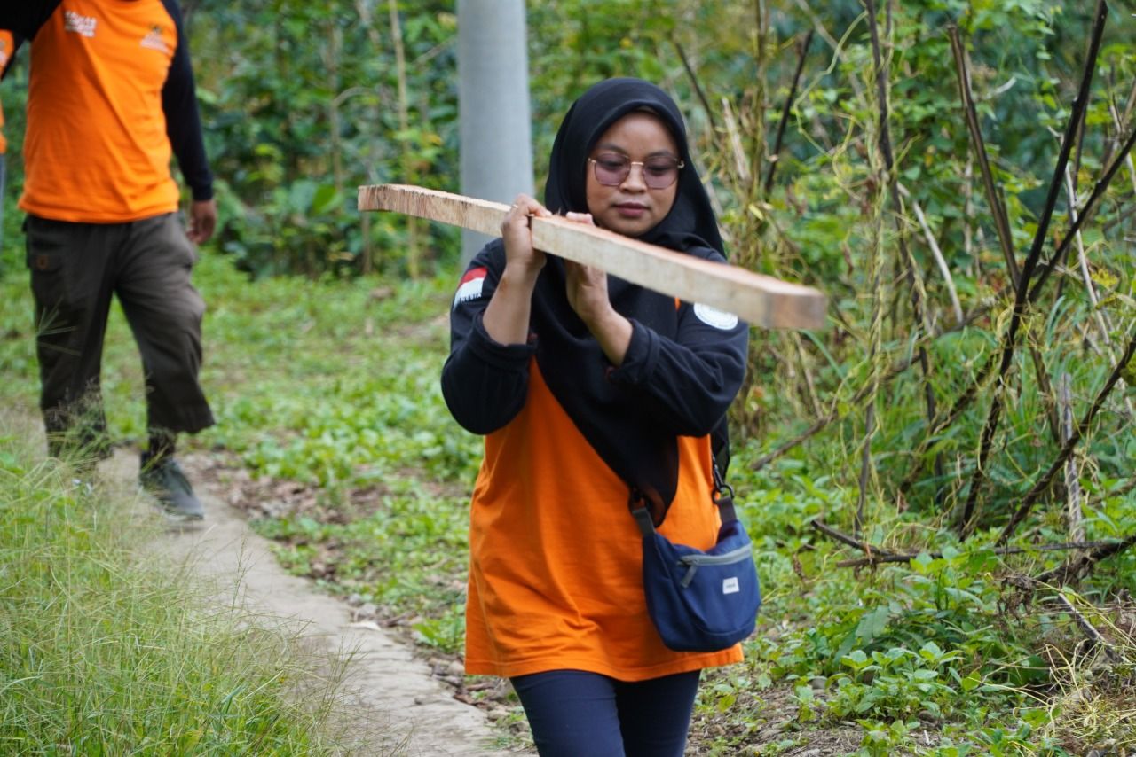 Salah satu relawan perempuan dari BTB Baznas Bulukumba memanggul balok  untuk renovasi Sekolah Alam di Benteng Senggang Kabupaten Bulukumba.