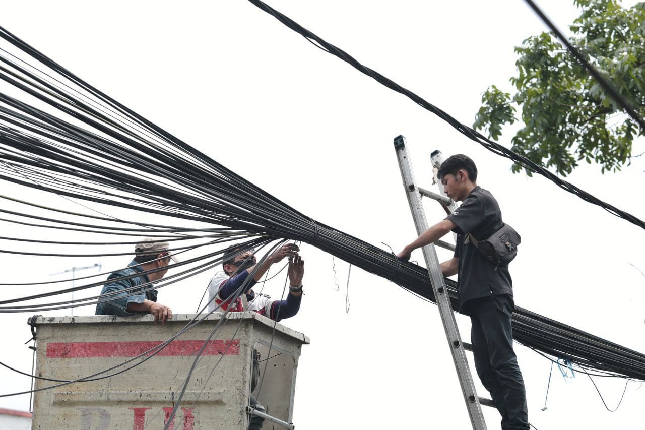Petugas menertibkan kabel yang melintang, di Kota Bandung 
