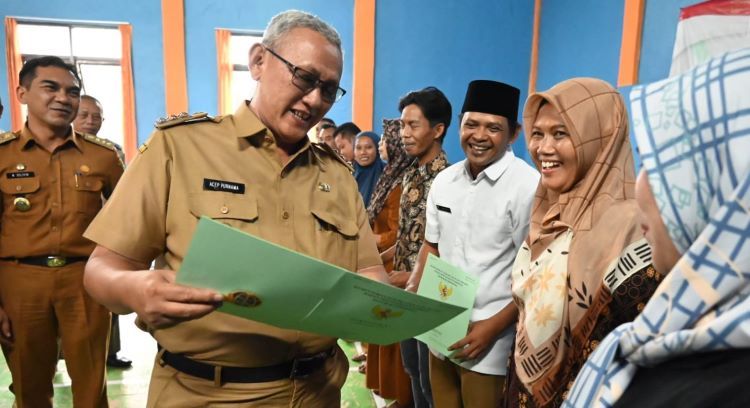 Bupati Kuningan, H. Acep Purnama menyerahkan sertifitkat tanah PTSL kepada warga Desa Mekarjaya Kecamatan Ciawigebang.