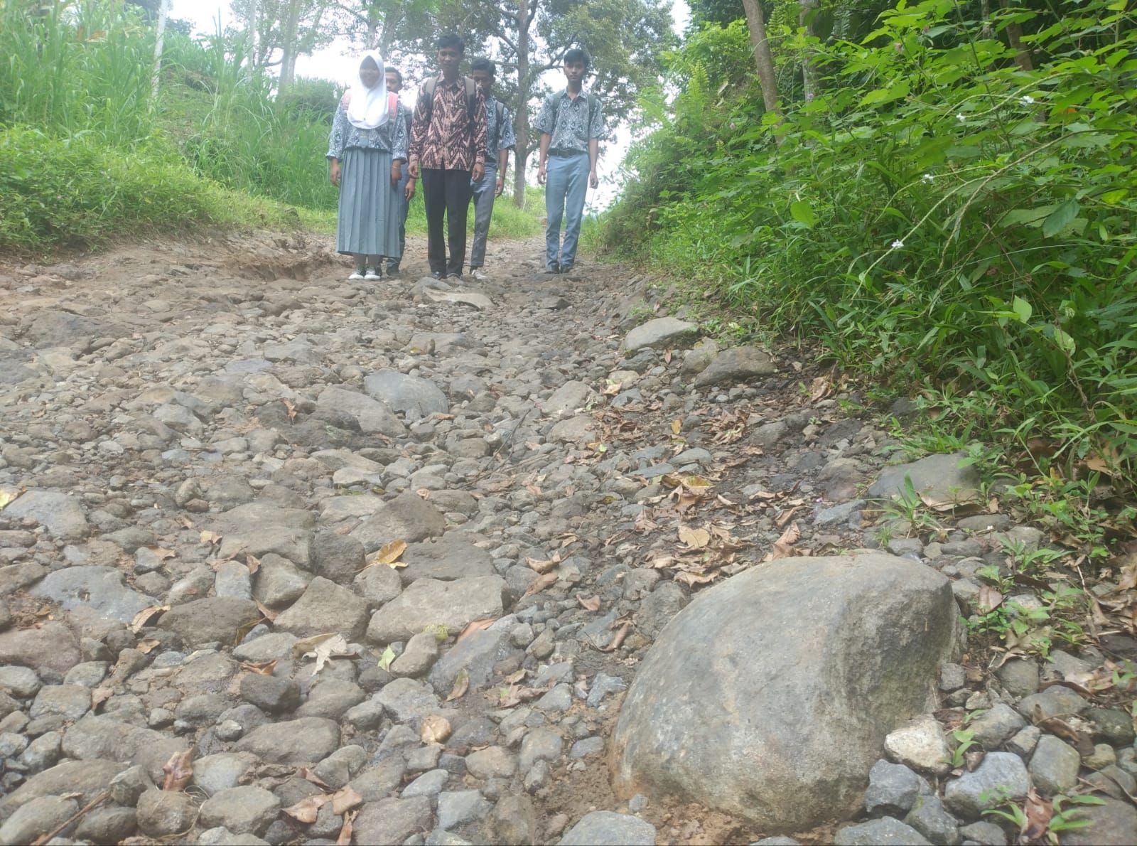  Guru dan siswa siswi SMAN 1 Salopa berjalan diantara medan jalan yang berbatu dan tidak diaspal