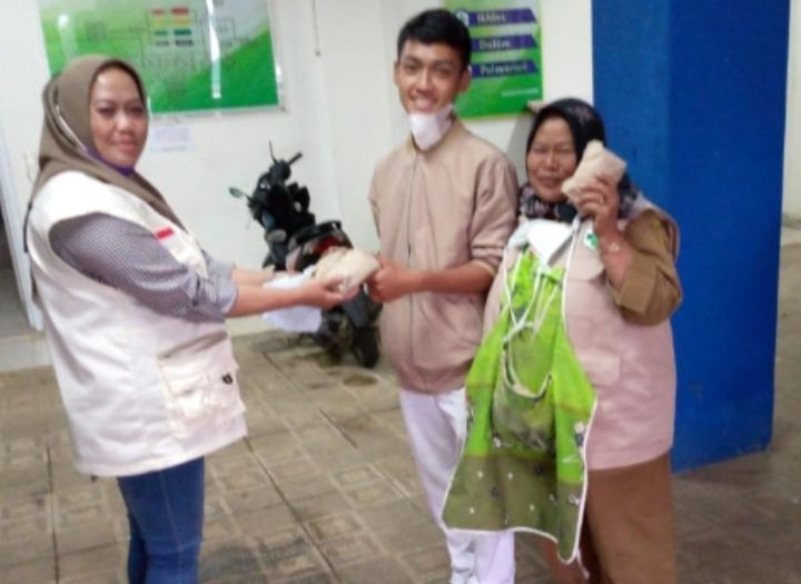 Salah satu pengurus BAGUNA KBB, Ai Hasanah serah terima bantuan nasi bungkus.