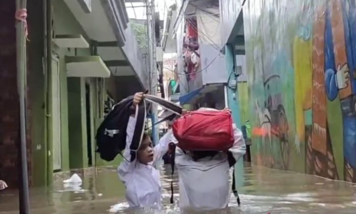 Dua siswa sekolah dasar (SD) sedang melewati banjir di permukiman Kebon Pala, Kelurahan Kampung Melayu, Kecamatan Jatinegara, Jakarta Timur, Jumat 24 Februari 2023.