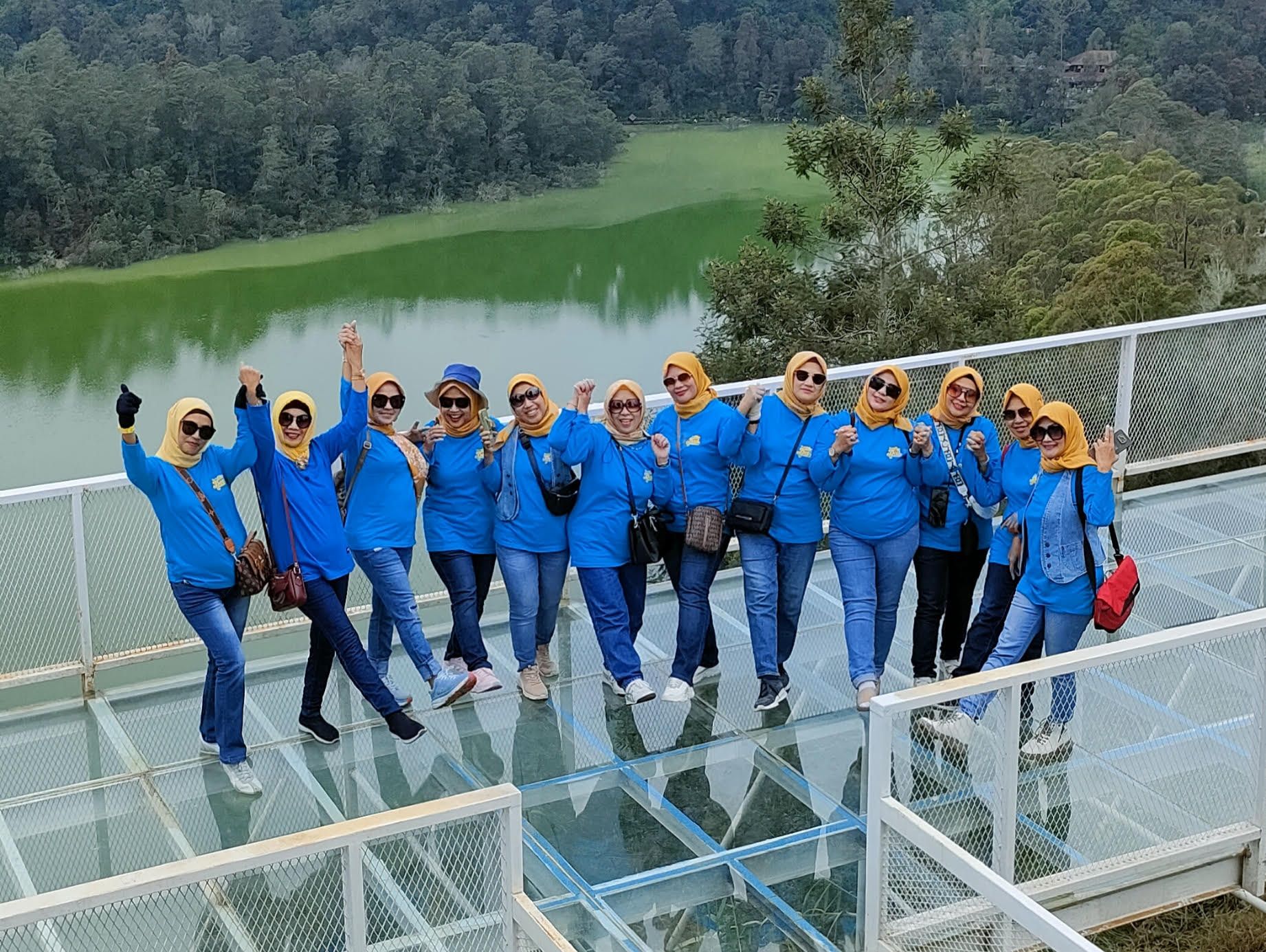 Salah satu rombongan wisatawan berfoto di jembatan kaca Dieng Park dengan latar belakang Telaga Warna yang eksotik.
