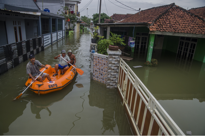 Warga menggunakan perahu karet melintasi genangan banjir di kawasan Karangligar, Kabupaten Karawang, Jawa Barat, Rabu (1/3/2023).
