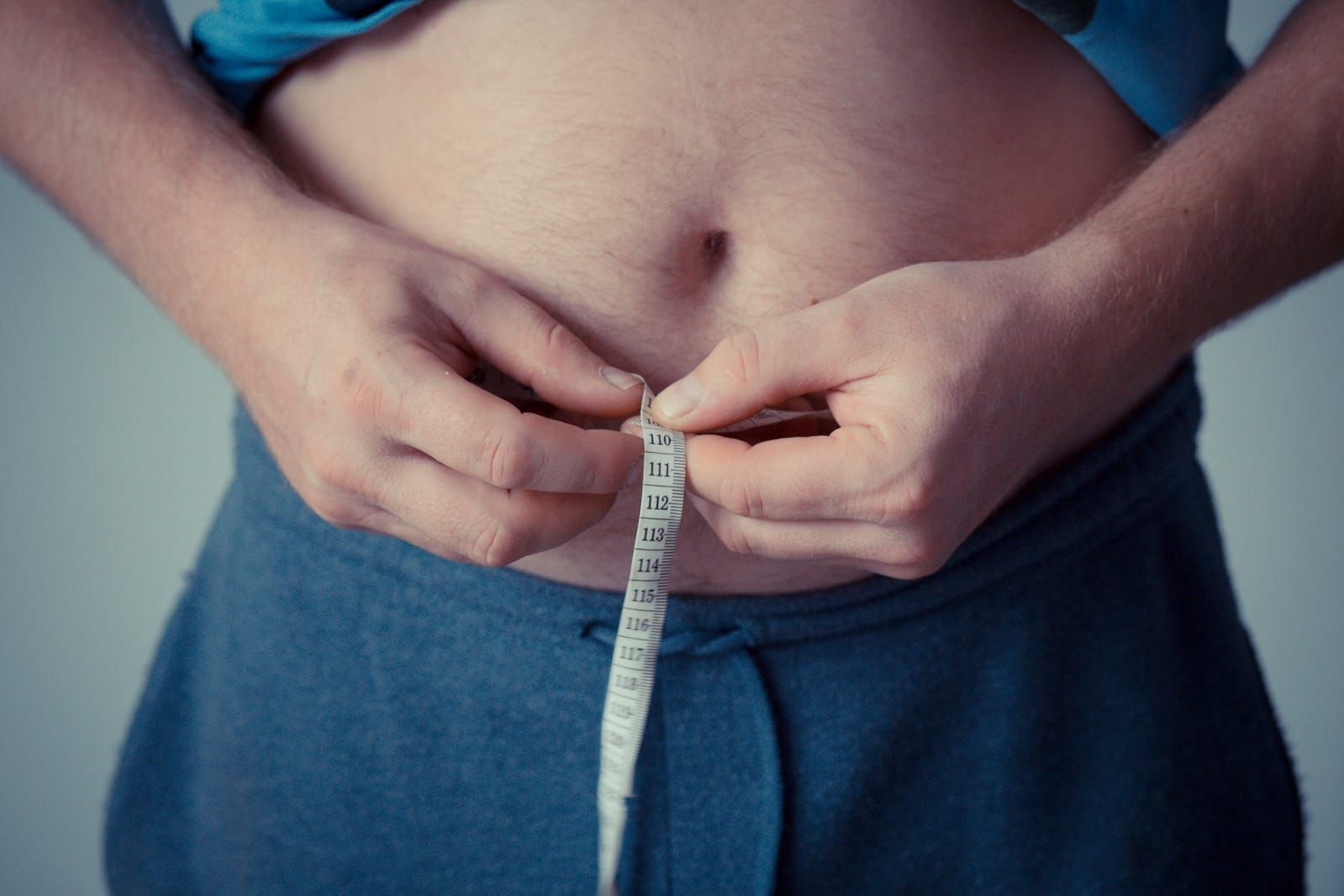 Ilustrasi seseorang mengukur lingkar perut sebagai tanda kelebihan berat badan atau obesitas.